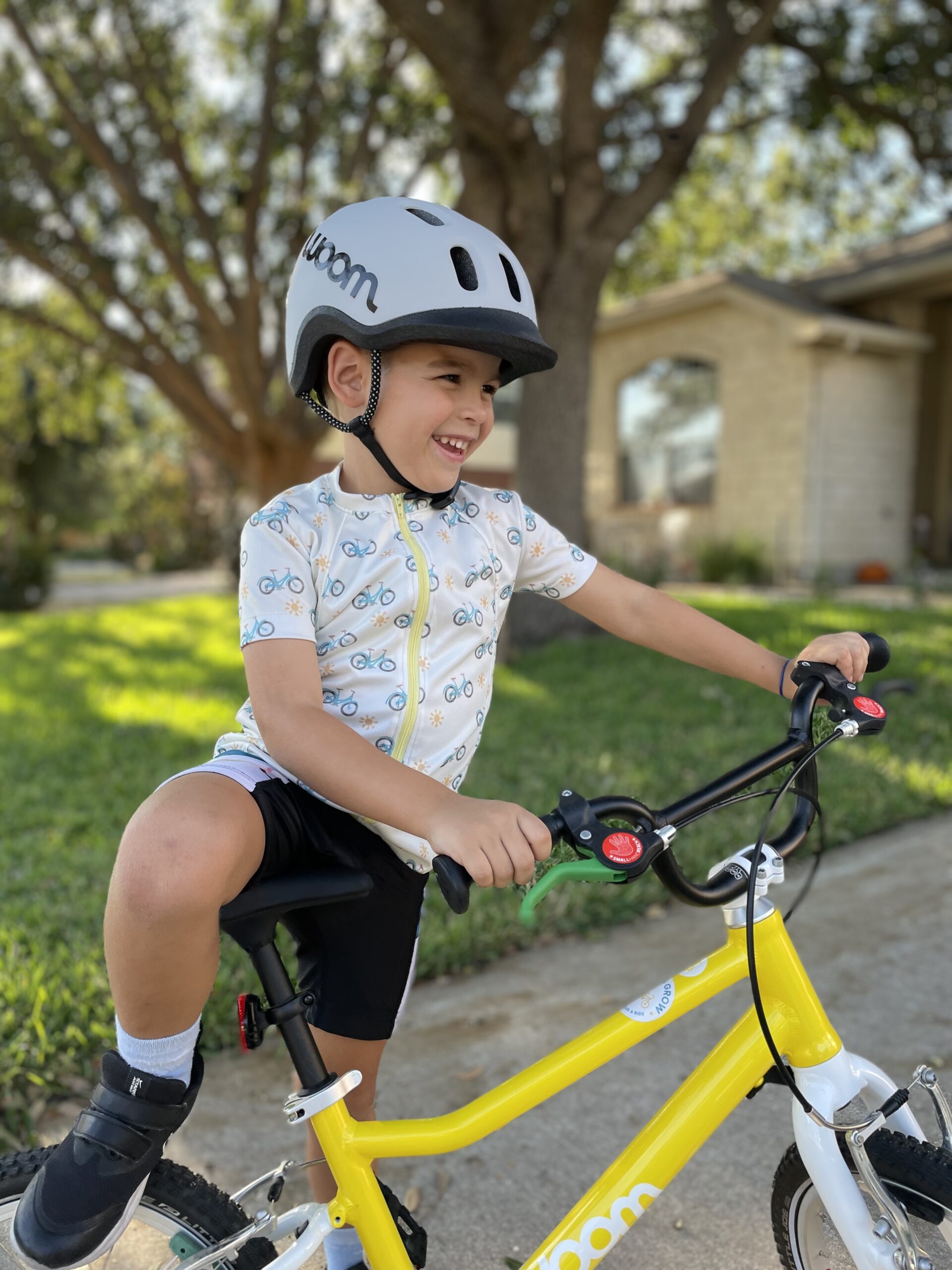 Happy kid riding Woom bike with Bike & Grow handmade jersey and grey Woom helmet